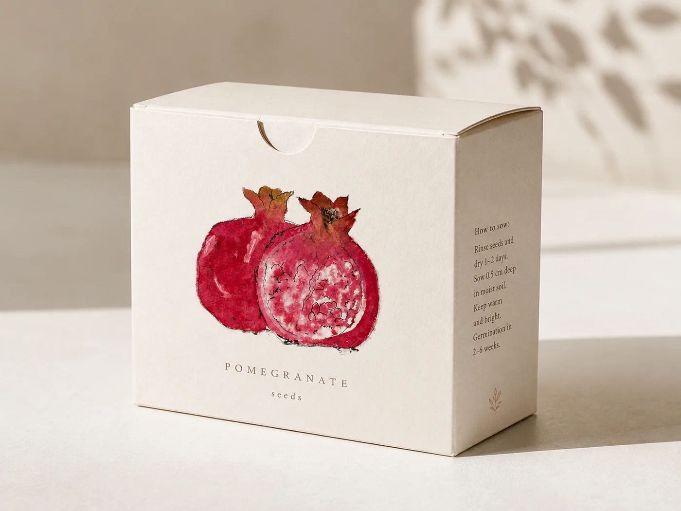 Cream seed packet box for pomegranate seeds, illustrated with a hand-painted watercolor pomegranate