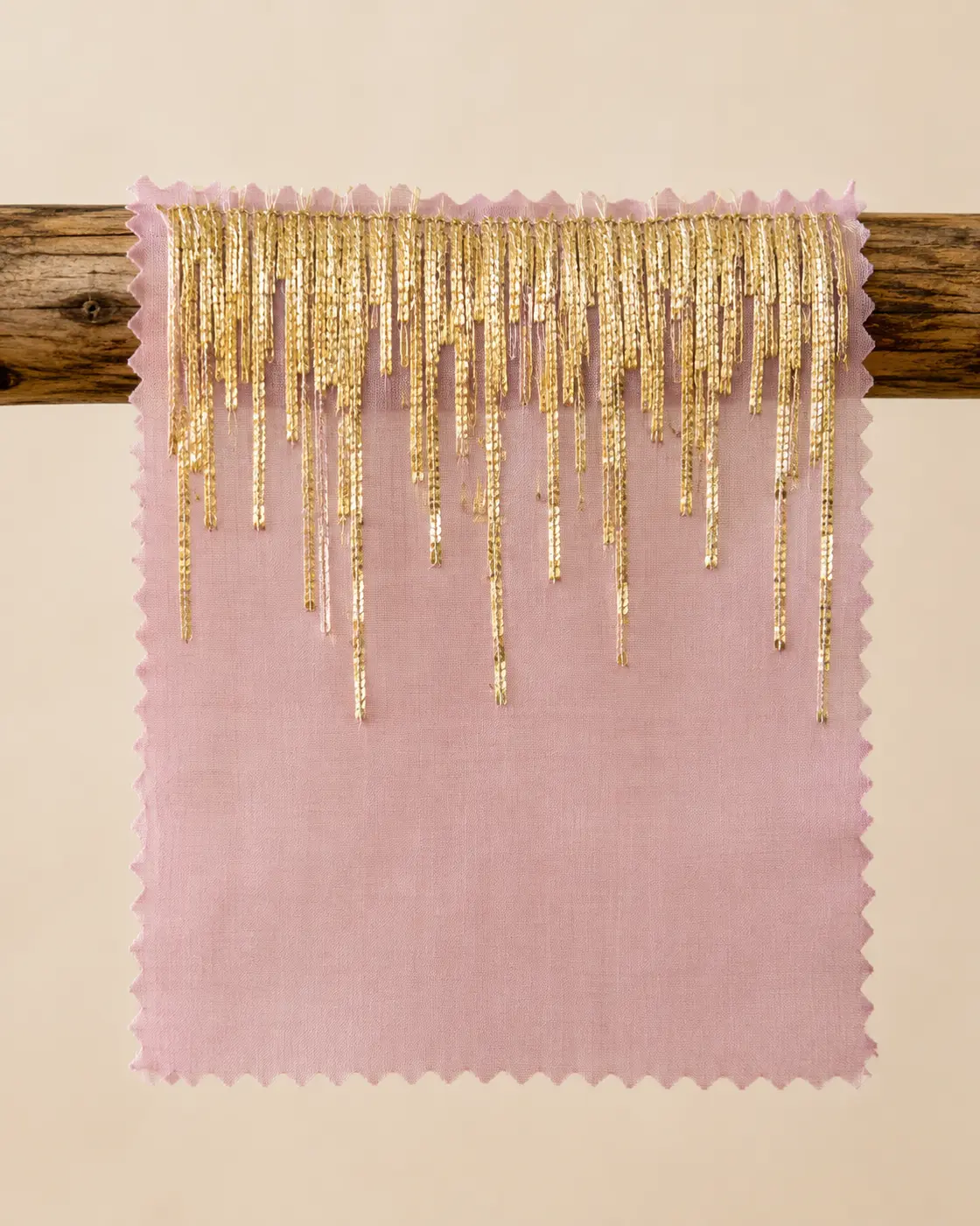 Blush pink swatch with cascading gold sequin fringe embroidery, hung on a wooden dowel